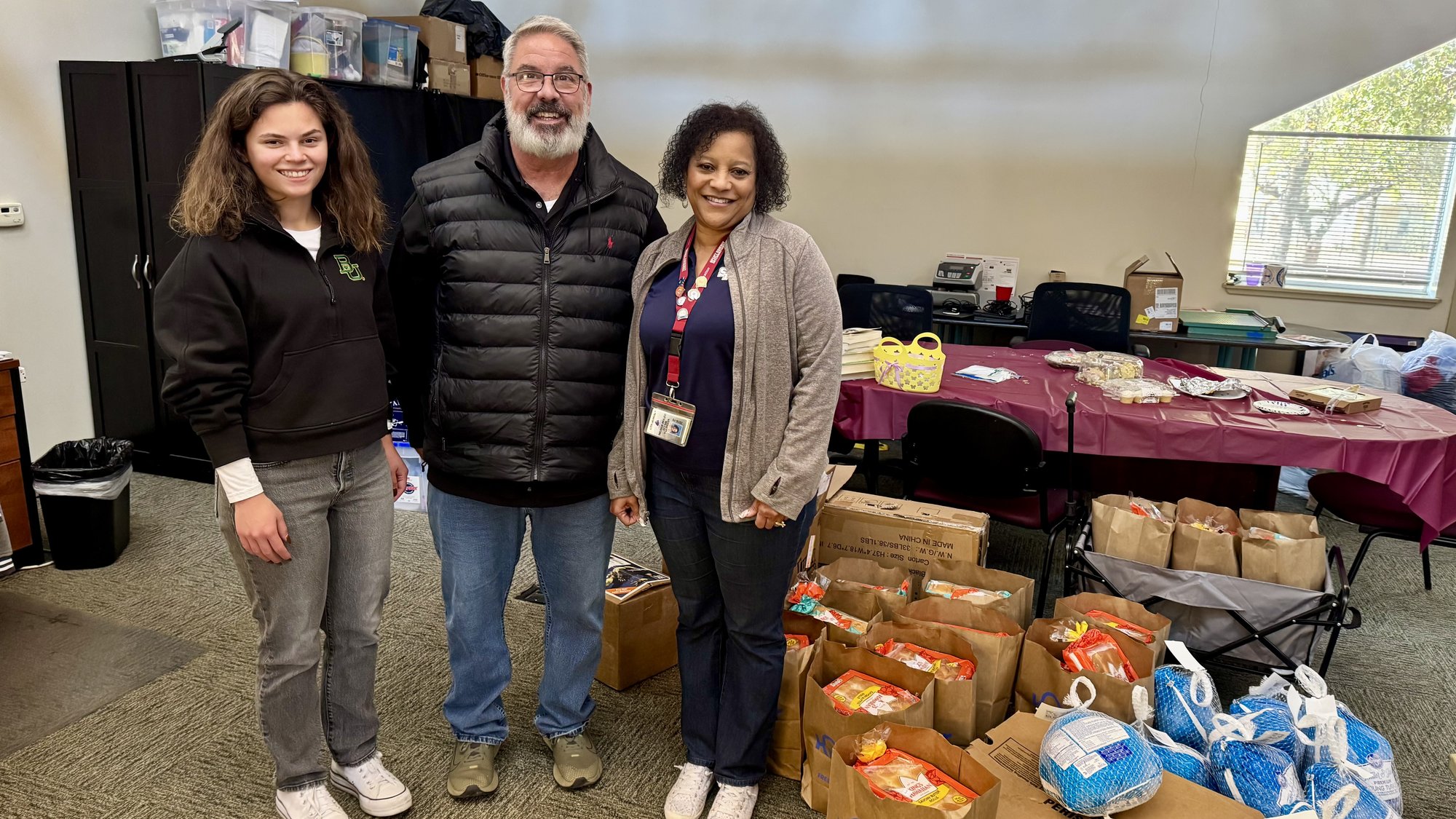 Three volunteers with bags of donated groceries at a community distribution